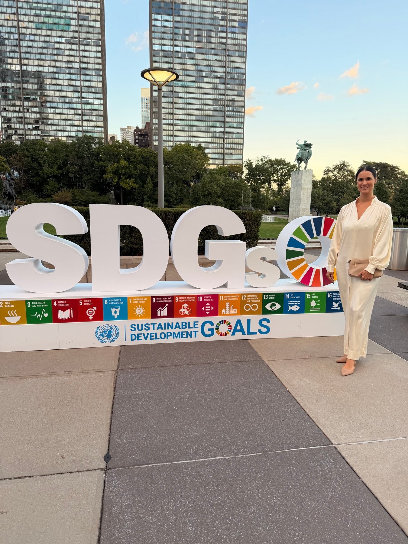 Juliana junto al cartel de los Objetivos de Desarrollo Sostenible en la sede de las Naciones Unidas